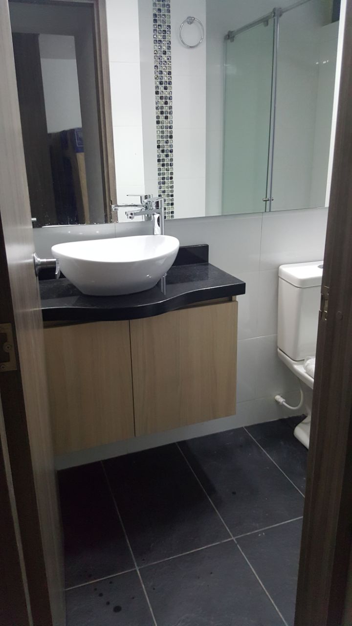 Baño privado con lavamanos ovalado tipo vessel y acabados en madera oscura.